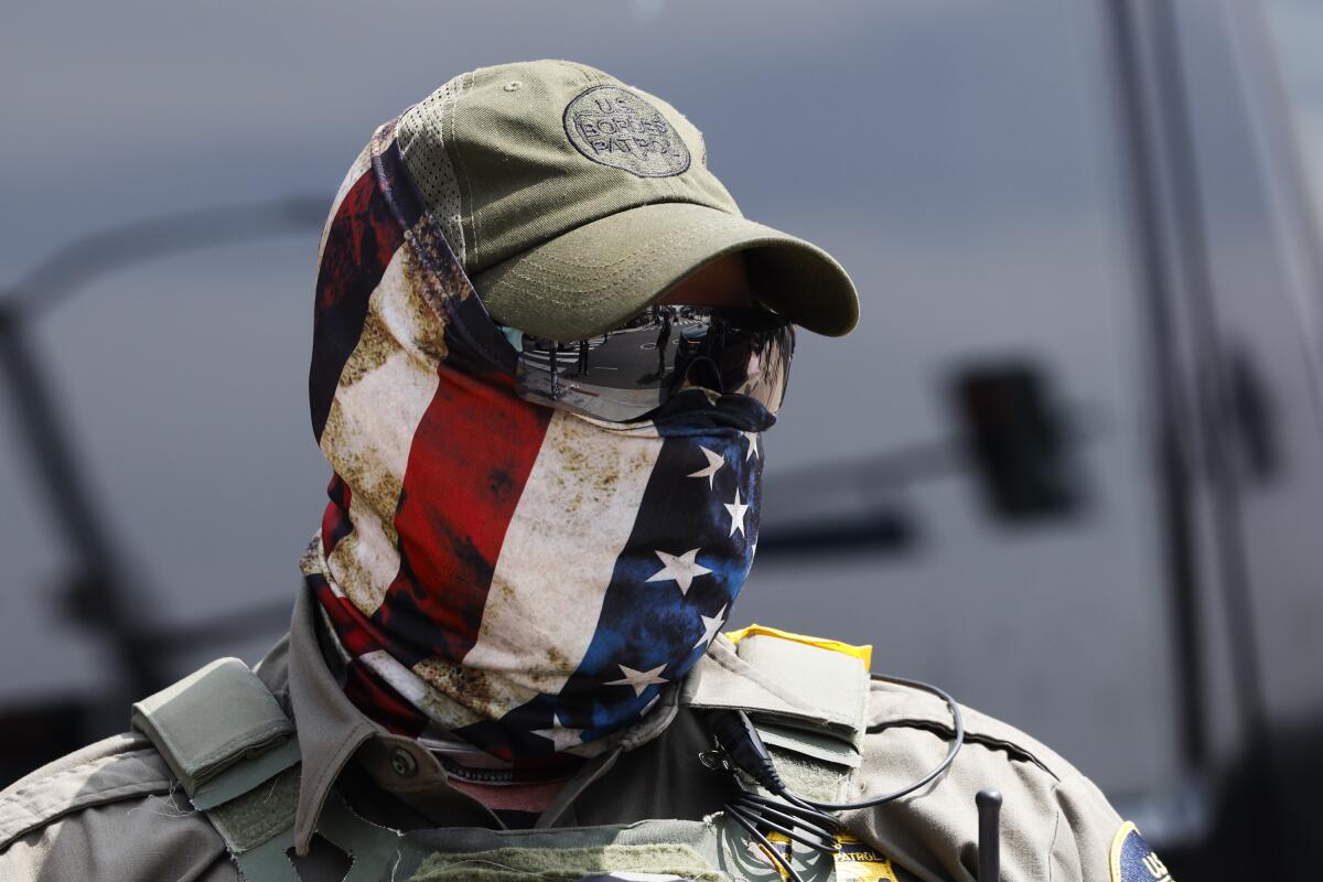 a man wearing a hat, sunglases, and an American flag as a face mask