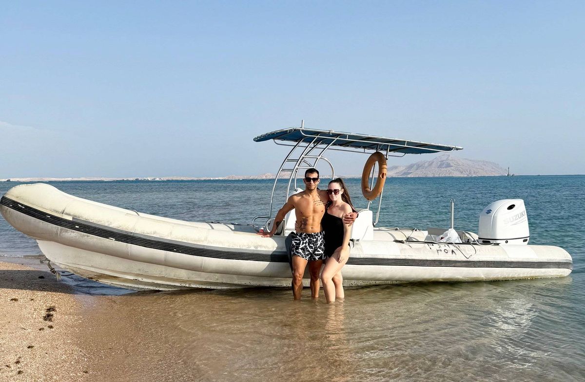 Shelley and her husband standing next to a boat