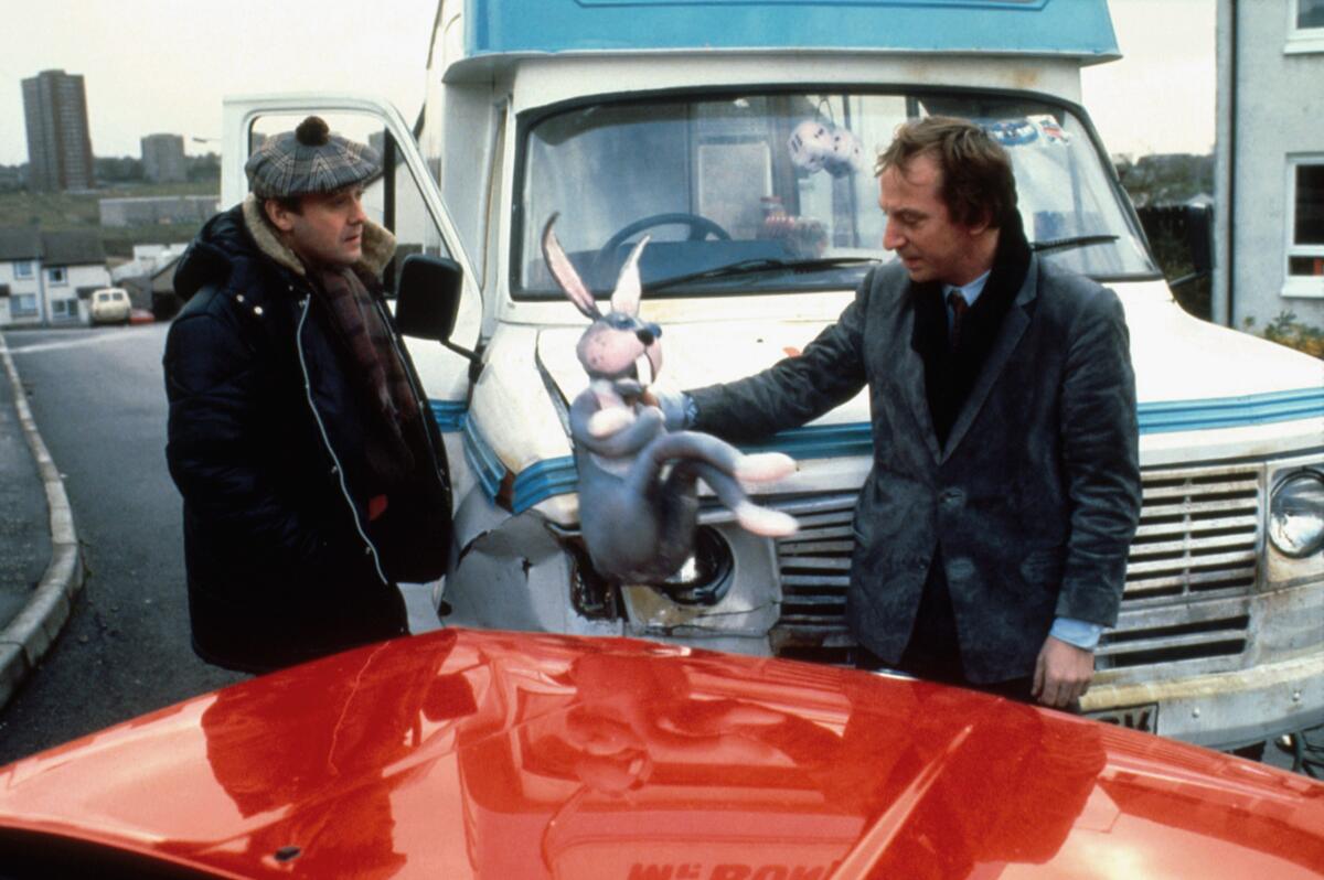 Two people stand outside and have a conversation.