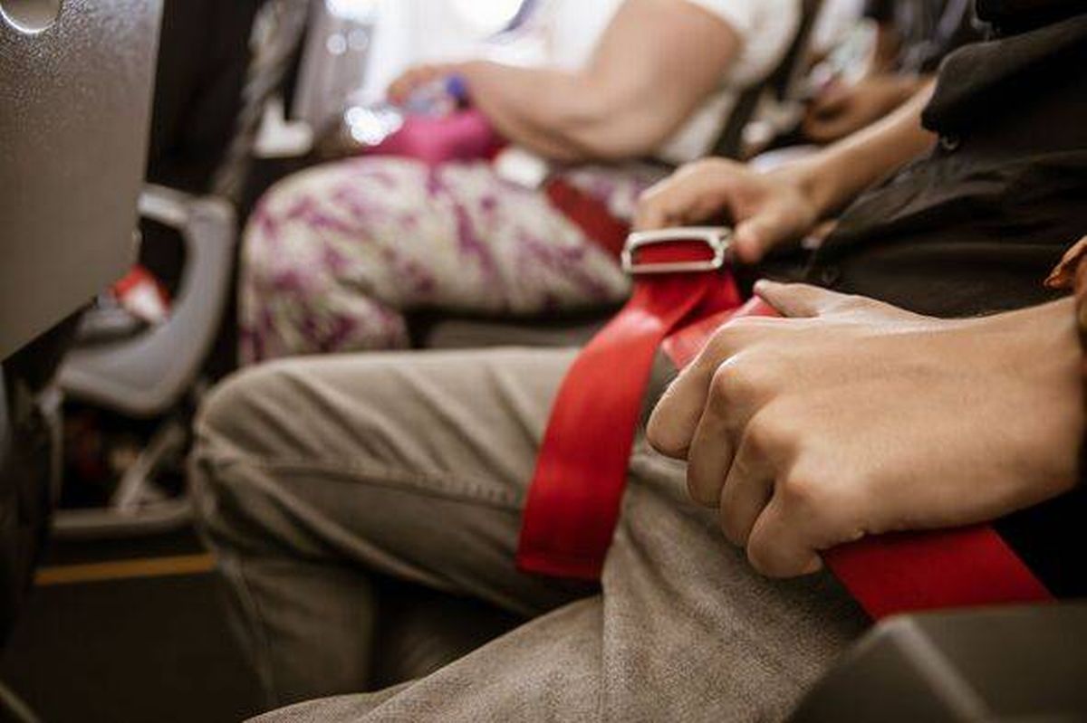 Plane passenger touching their seatbelt 