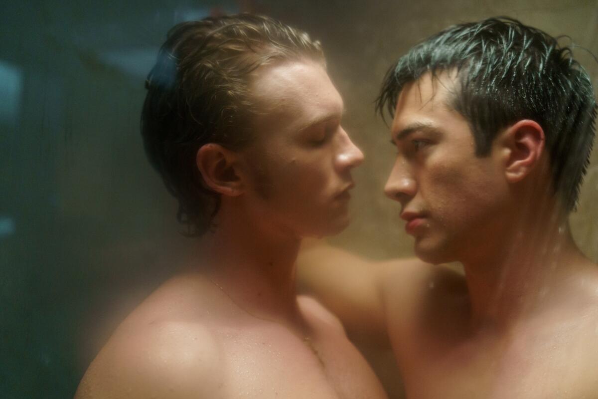 Two men in a shower leaning toward one another.