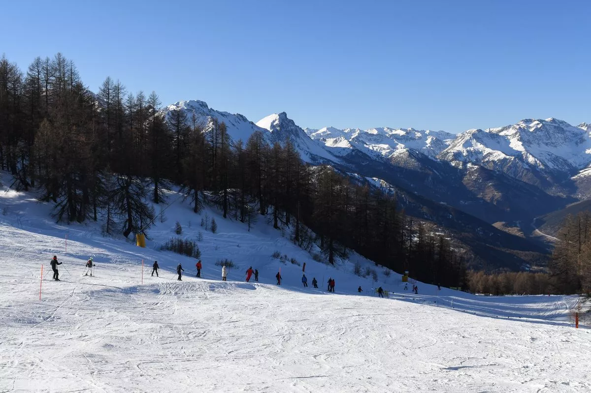 Skiers and snowboarders descending a ski slope in Sauze D'Oulx ski resort