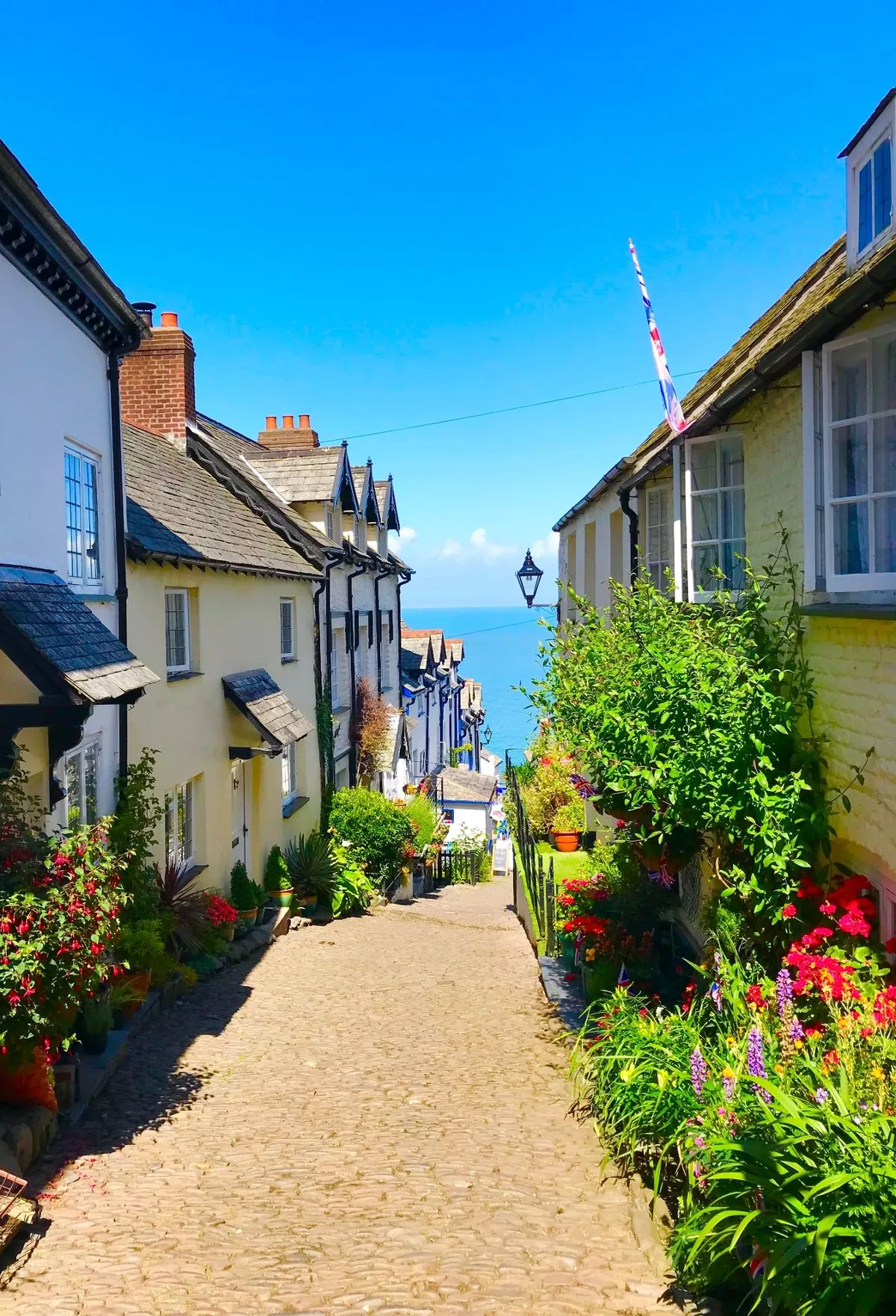 cobbled street with cottages either side and ocean in distance