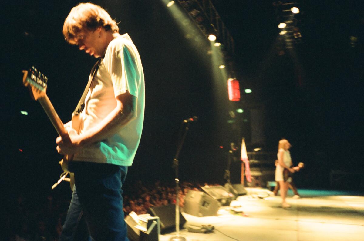 A rock band performs onstage in the 1990s.