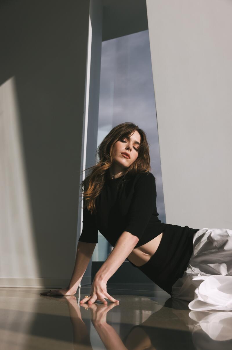 A woman lays on her side on the floor, holding herself up with her hands.