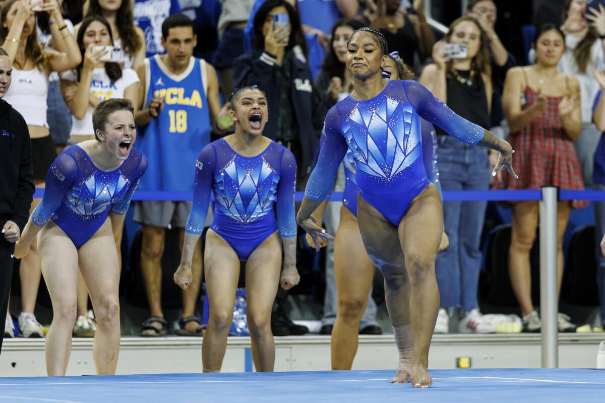 UCLA gymnasts, from left, Nola Matthews and Tiana Sumanasekera cheer as Jordan Chiles lands a jump during her floor routine.