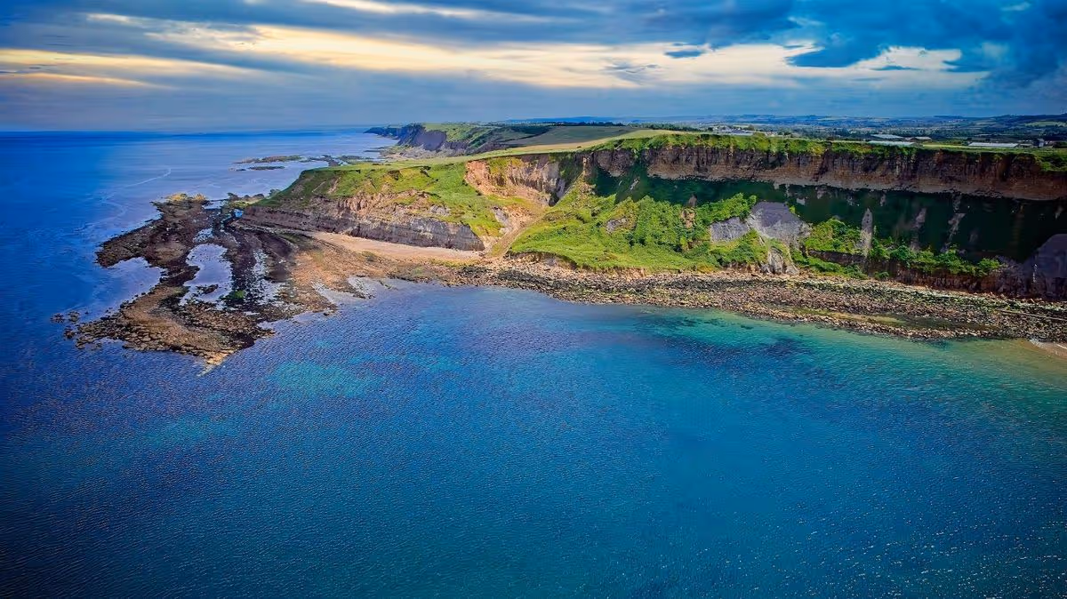 Aerial view of coastal cliff and clear blue waters at Cayton Bay, Yorkshire