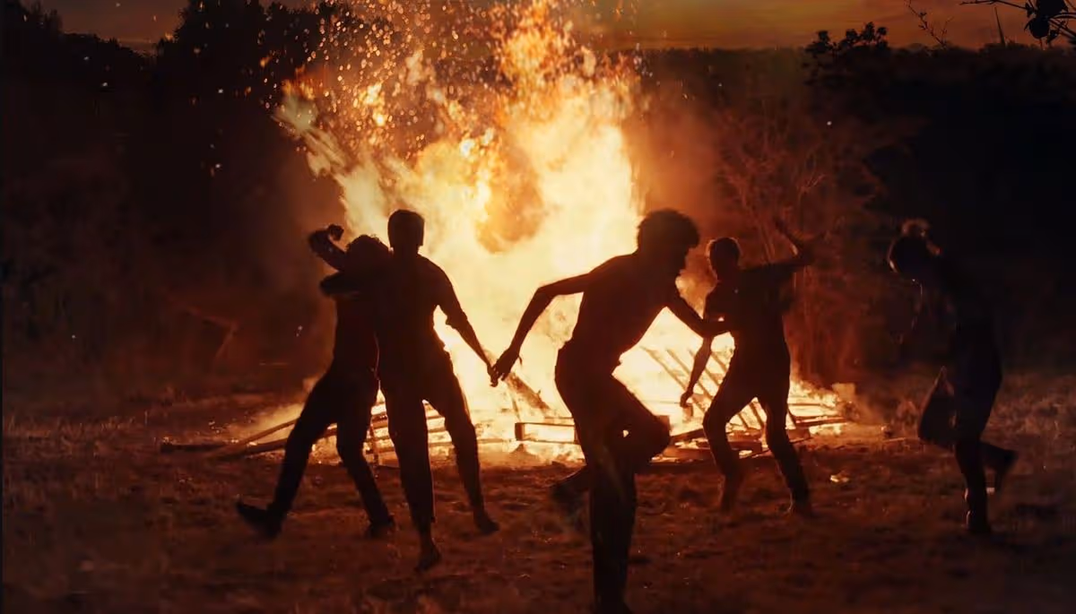 Group of teenagers dancing in front of a bonfire
