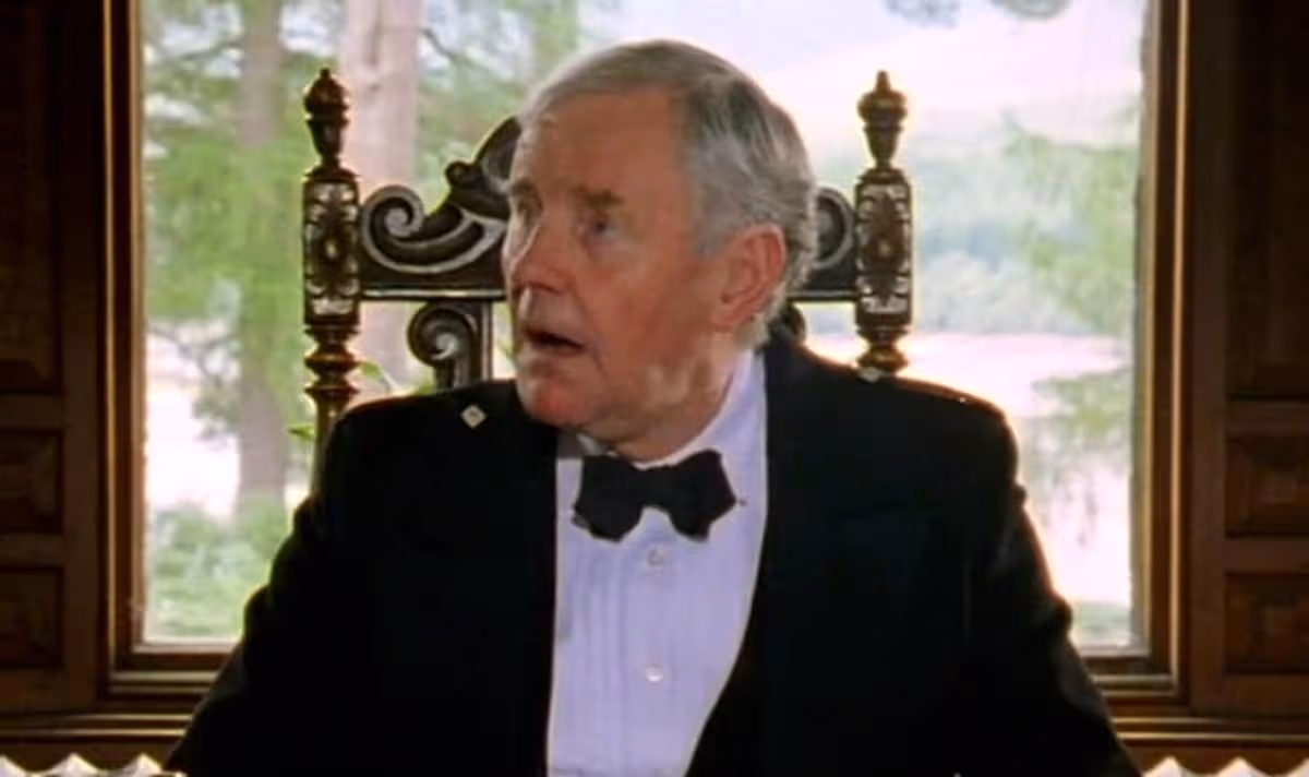 A man in a suit sits and speaks