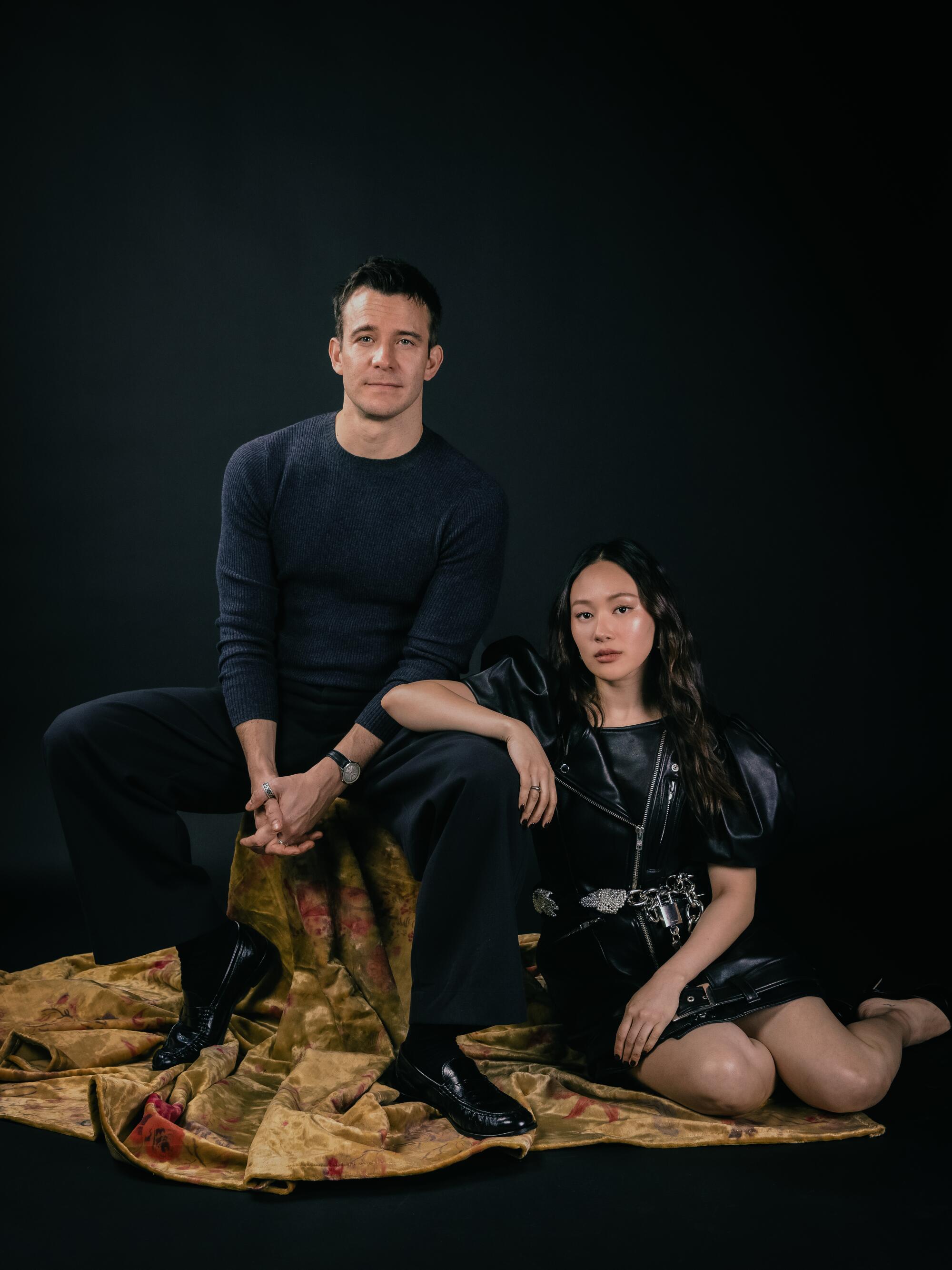 A man and a woman post for a photo around a stool draped in fabric
