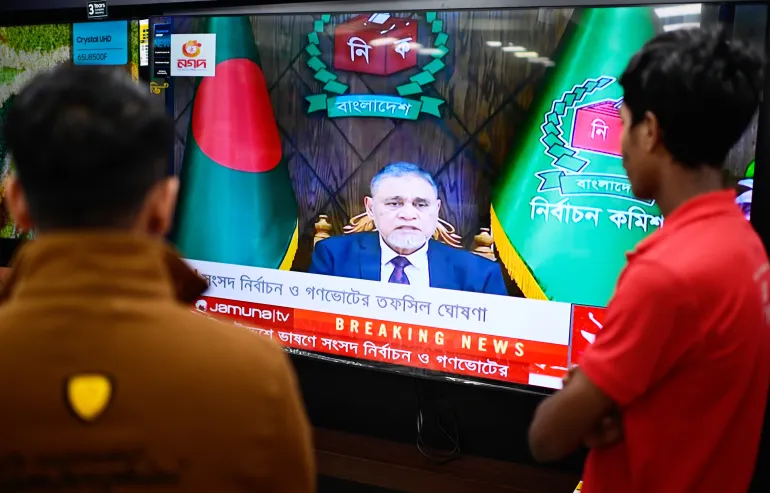 People watch Bangladesh's Chief Election Commissioner A.M.M. Nasir Uddin's address to the nation on a television, in Dhaka, Bangladesh, Thursday, Dec. 11, 2025. (AP Photo/Mahmud Hossain Opu)