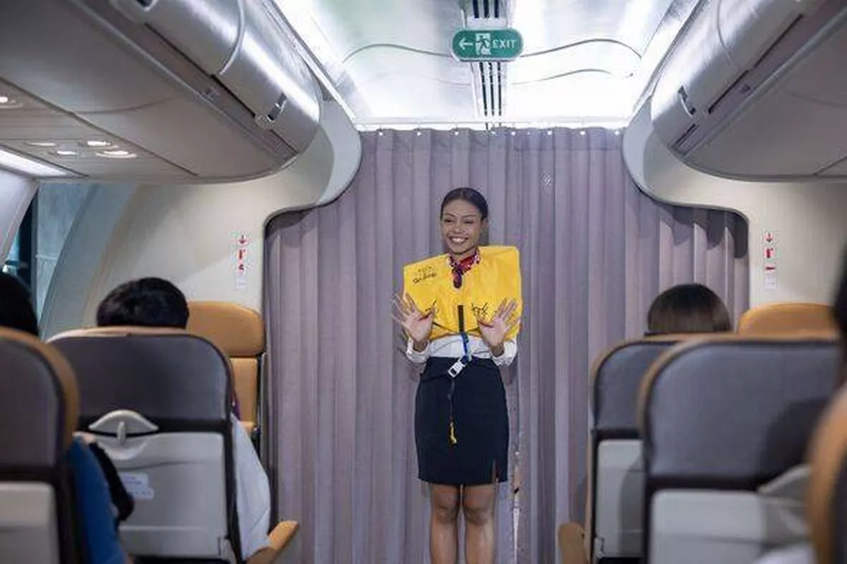 Flight attendant is demonstrating safety procedure using life jacket before taking off inside airplane for cabin crew and airline business