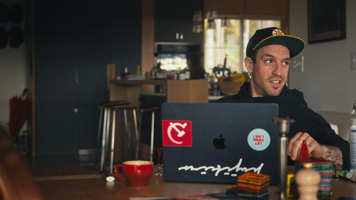 A man in a baseball cap smiles at a laptop.