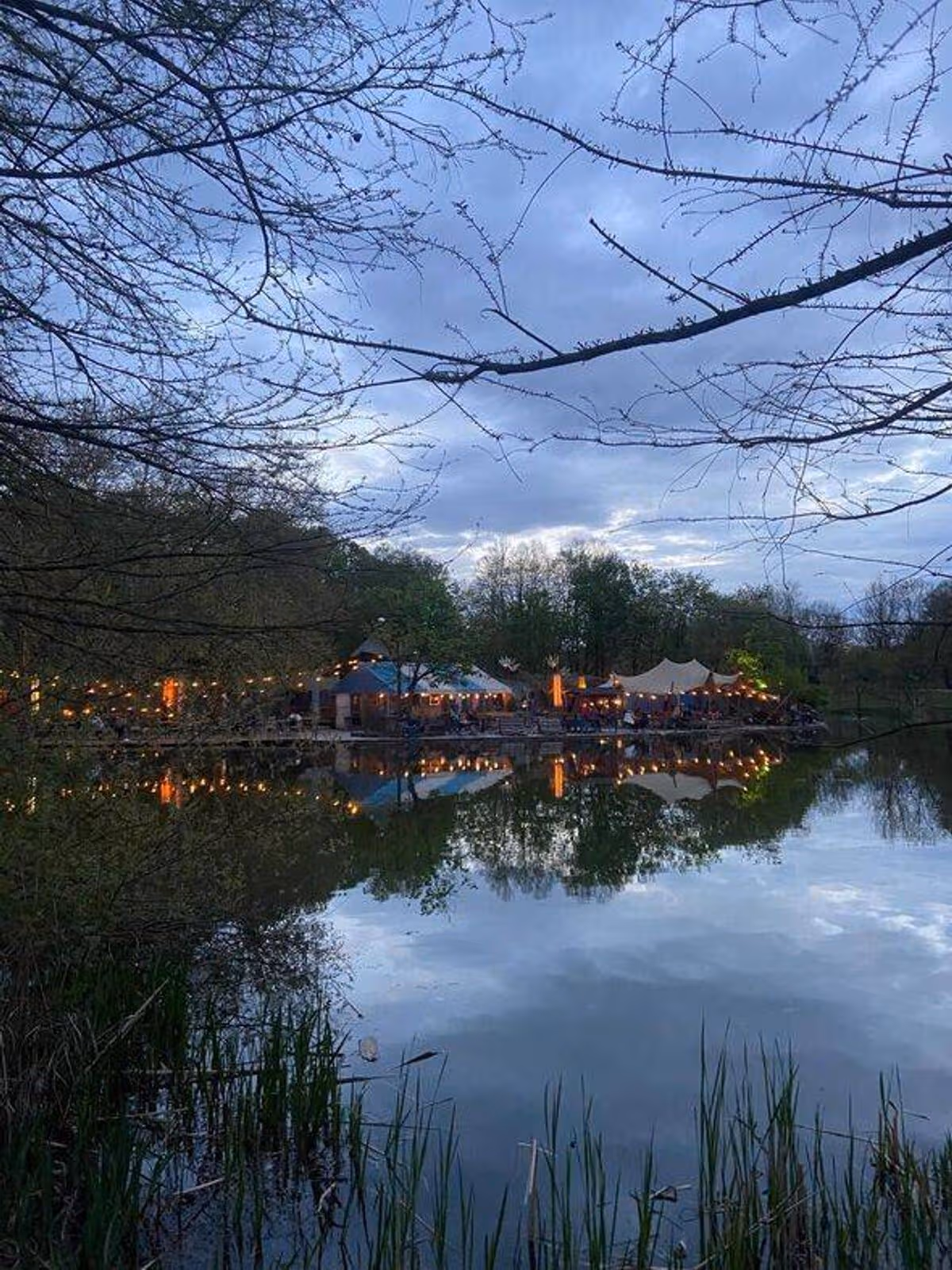 A beer garden in Munich across a pond at sunset hour