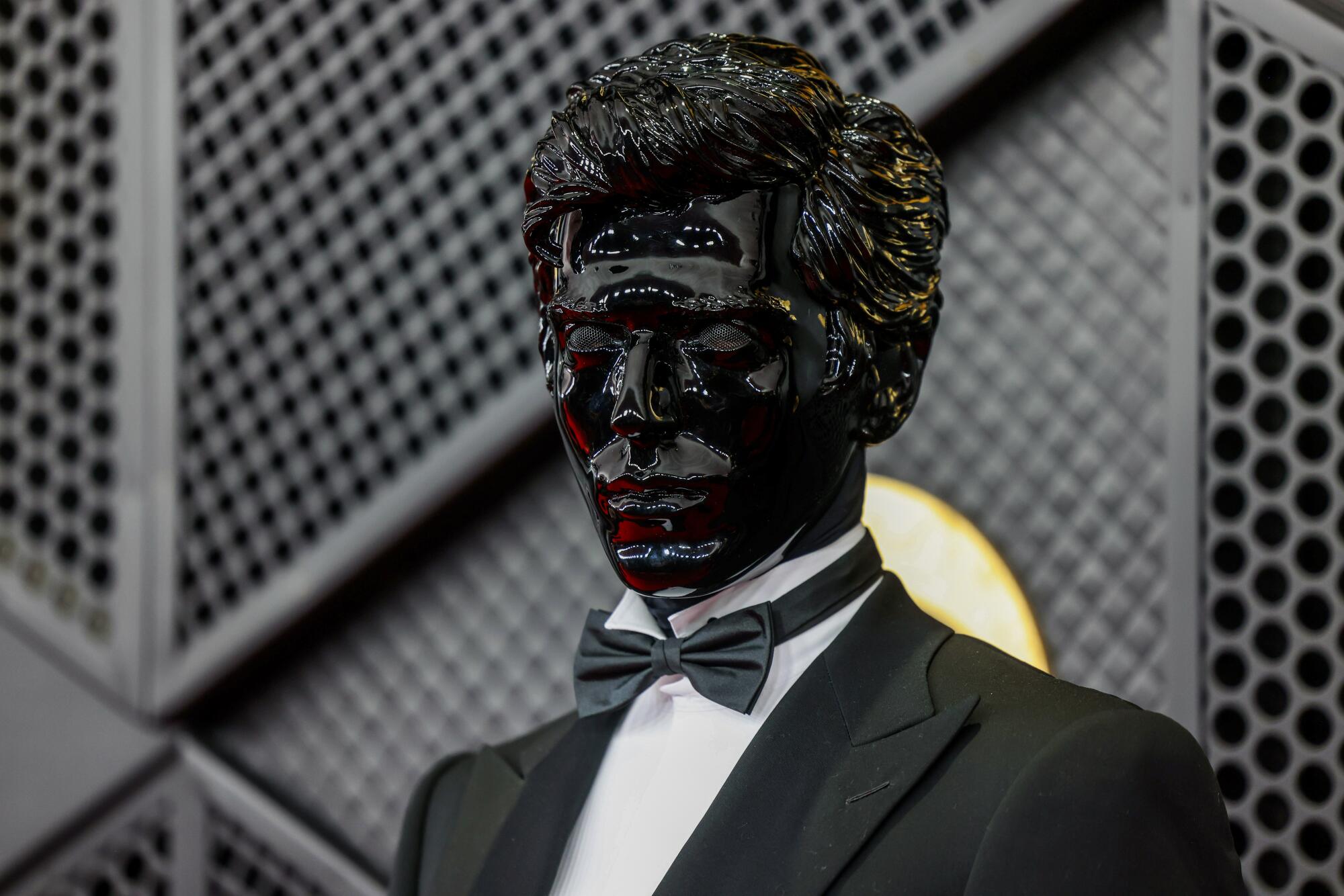 Gesaffelstein, in a black mask, poses on the red carpet. 