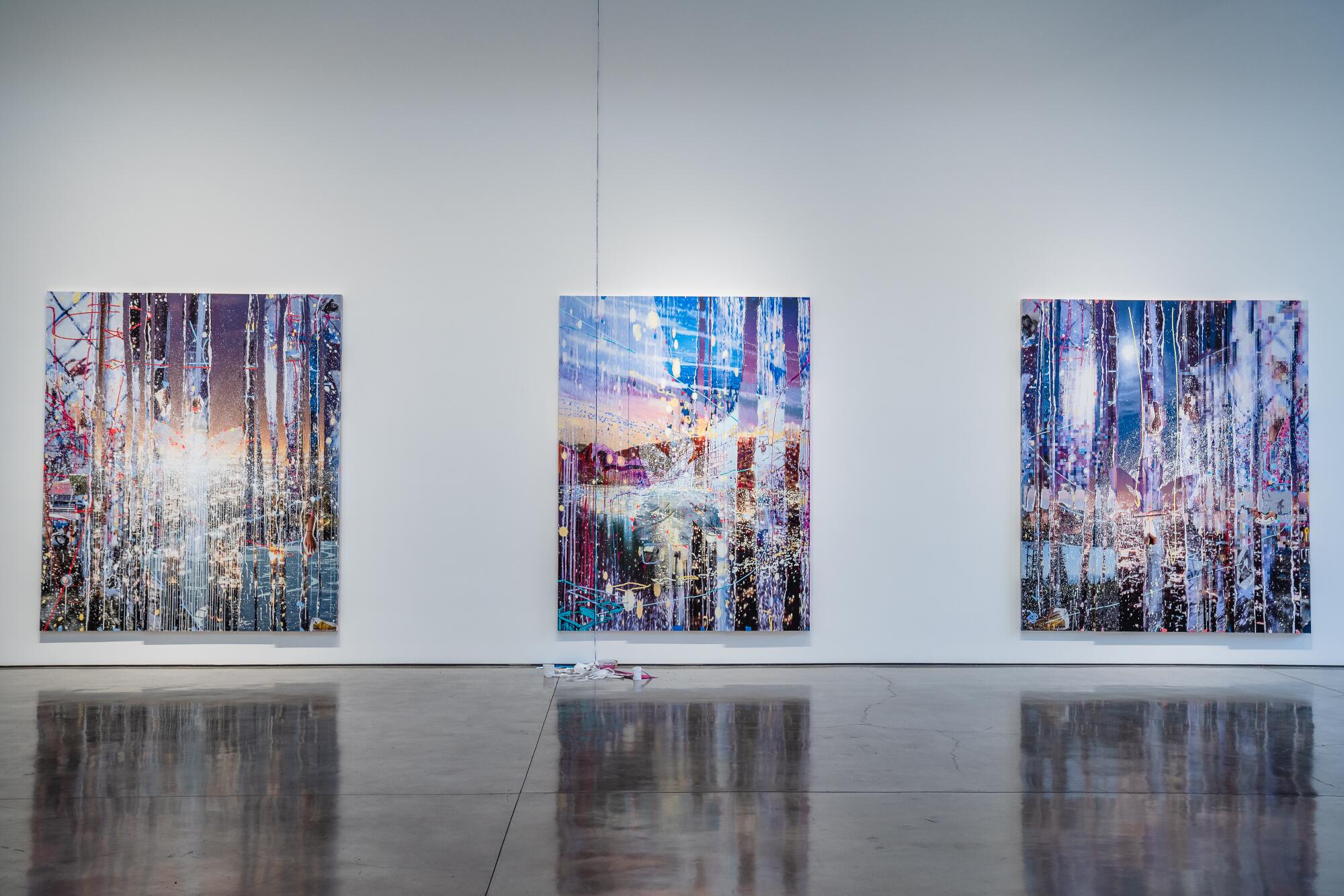 Three large paintings hang on a white gallery wall.